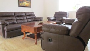 A living room with a brown leather sofa, a matching armchair, and a wooden coffee table.