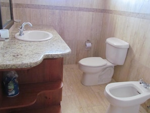 Un baño con lavamanos de encimera de granito, un inodoro y un bidé.