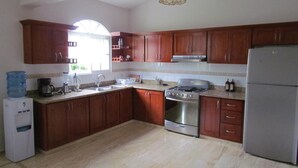 A kitchen with wooden cabinets, a stainless steel stove, a refrigerator, and a water dispenser.