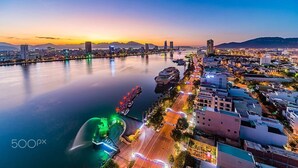A cityscape at dusk with a river, buildings, and a bridge. - Sunny Studio with balcony ★ Steps to Dragon Bridge (Đà Nẵng)