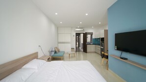A modern hotel room with a large bed, a TV, and a kitchenette area. - Sunny Studio with balcony ★ Steps to Dragon Bridge (Đà Nẵng)