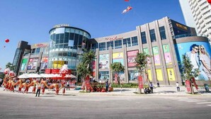 A modern building with a curved glass facade, a prominent sign, and a large billboard. - Sunny Studio with balcony ★ Steps to Dragon Bridge (Đà Nẵng)
