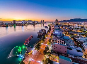 A cityscape at dusk with a river, buildings, and a bridge. - Sunny Studio with balcony ★ Steps to Dragon Bridge (Đà Nẵng)