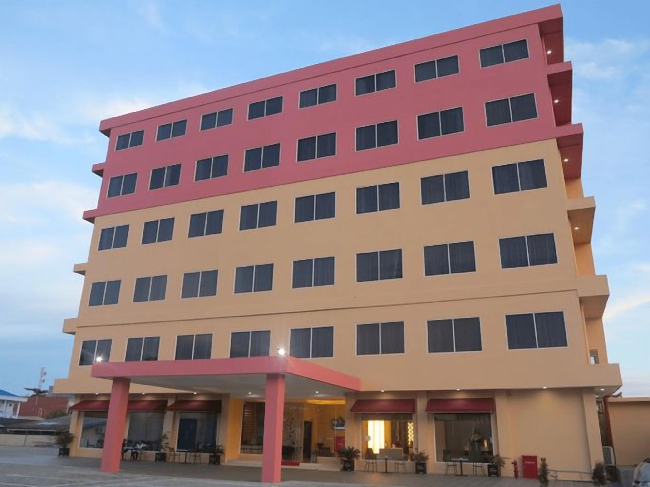 A multi-story hotel with a flat facade, multiple balconies, and a covered entrance area.