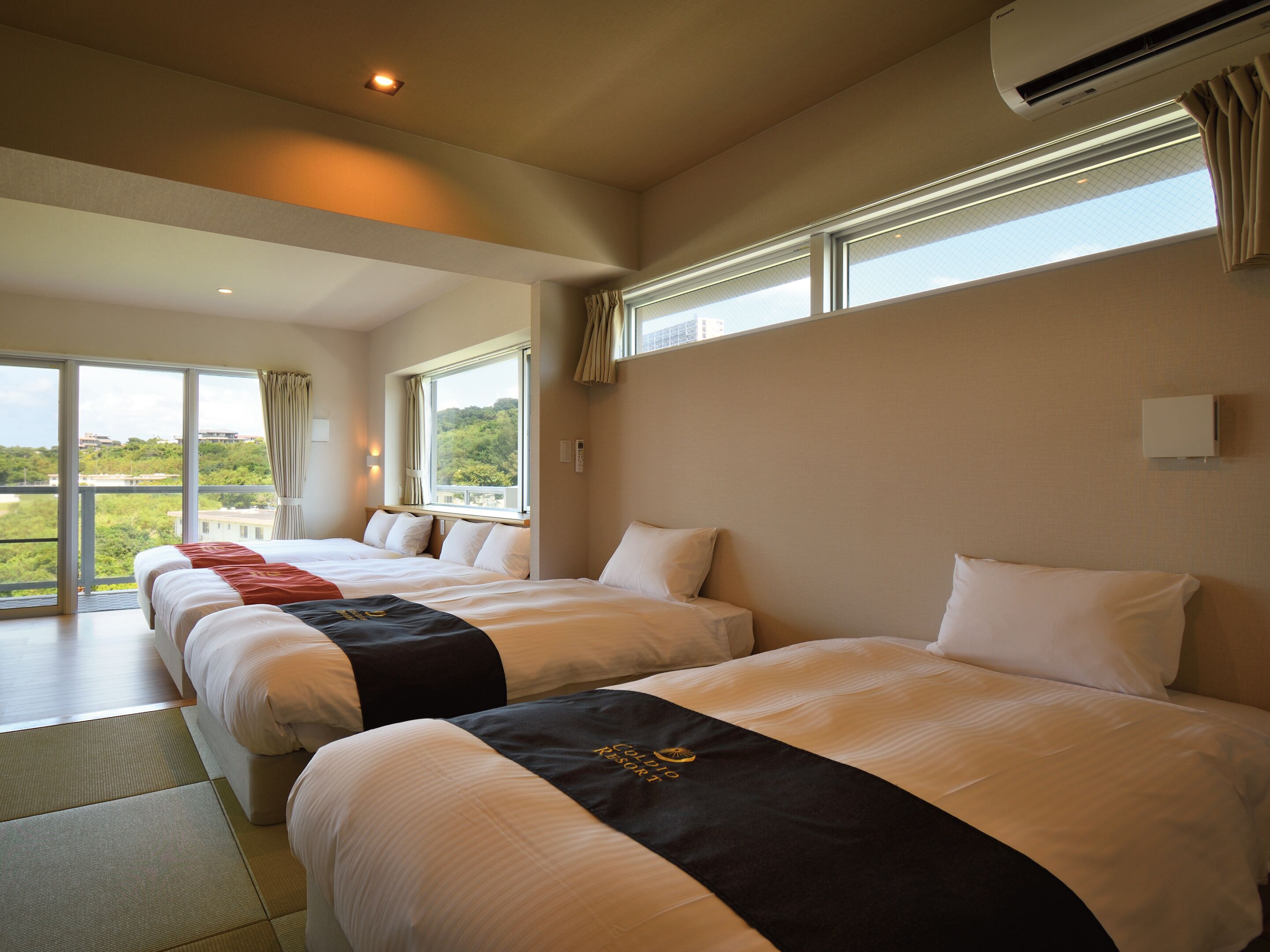 Ein Hotelzimmer mit zwei Betten, großen Fenstern und einer Klimaanlage.