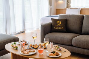 A dining area with a table set for a meal, a sofa with a pillow, and a bed in the background. - Private Condo Chatan Jagaru by Coldio Premium (Chatan)