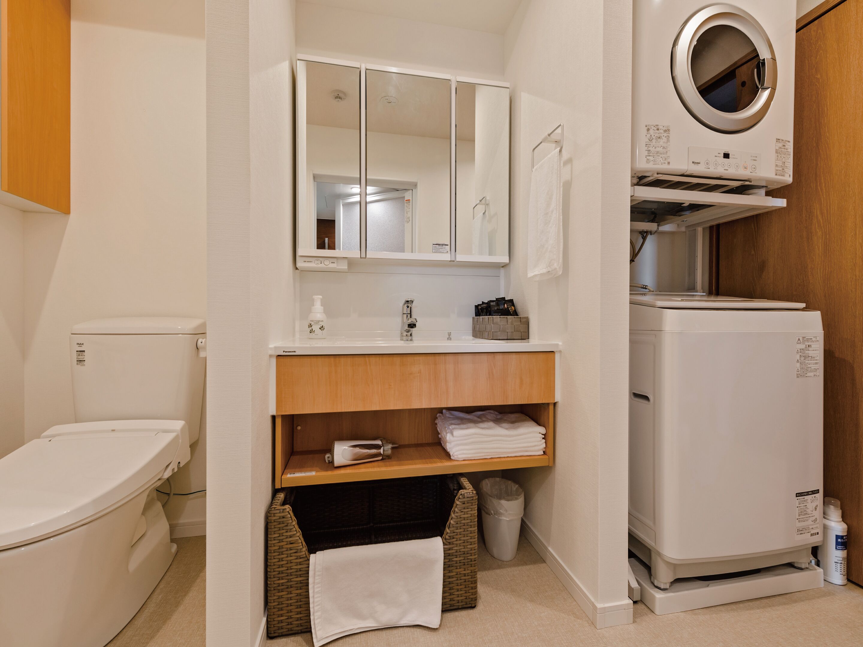 Une salle de bain équipée de toilettes, d’un lavabo, d’un miroir et d’un lave-linge.