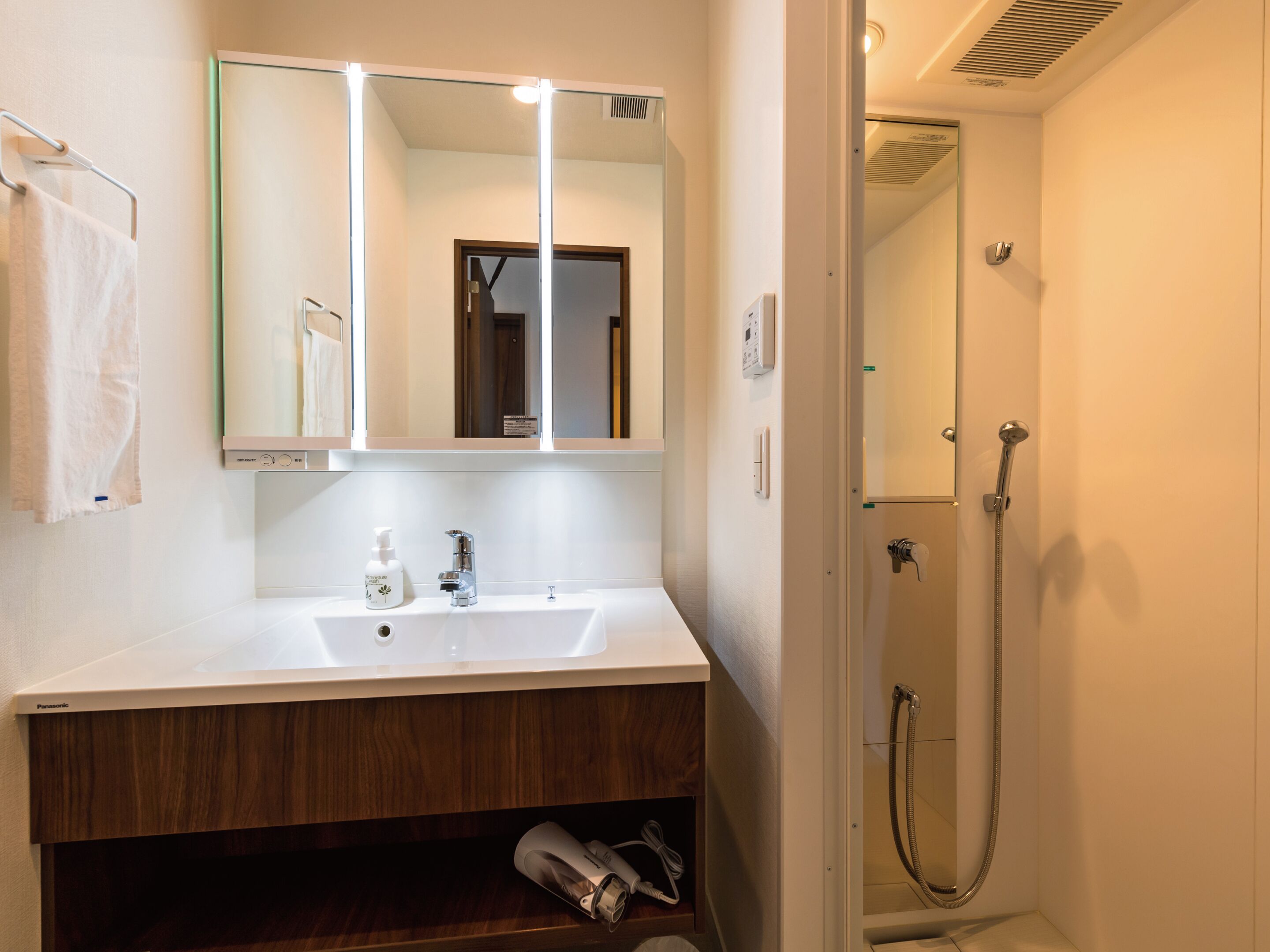 A bathroom with a white sink, a mirror, and a shower.