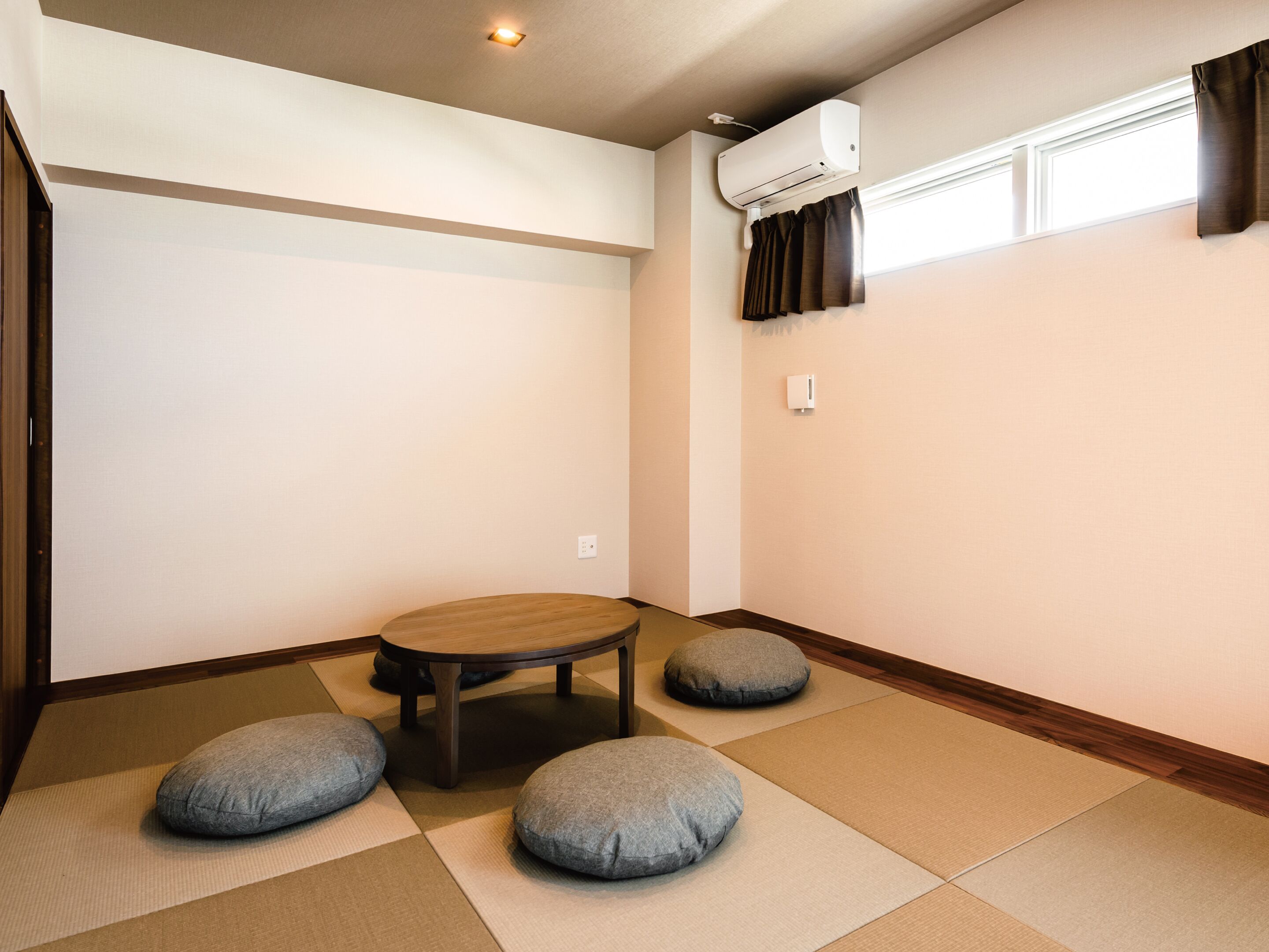 A room with tatami mats, a low wooden table, and cushions.