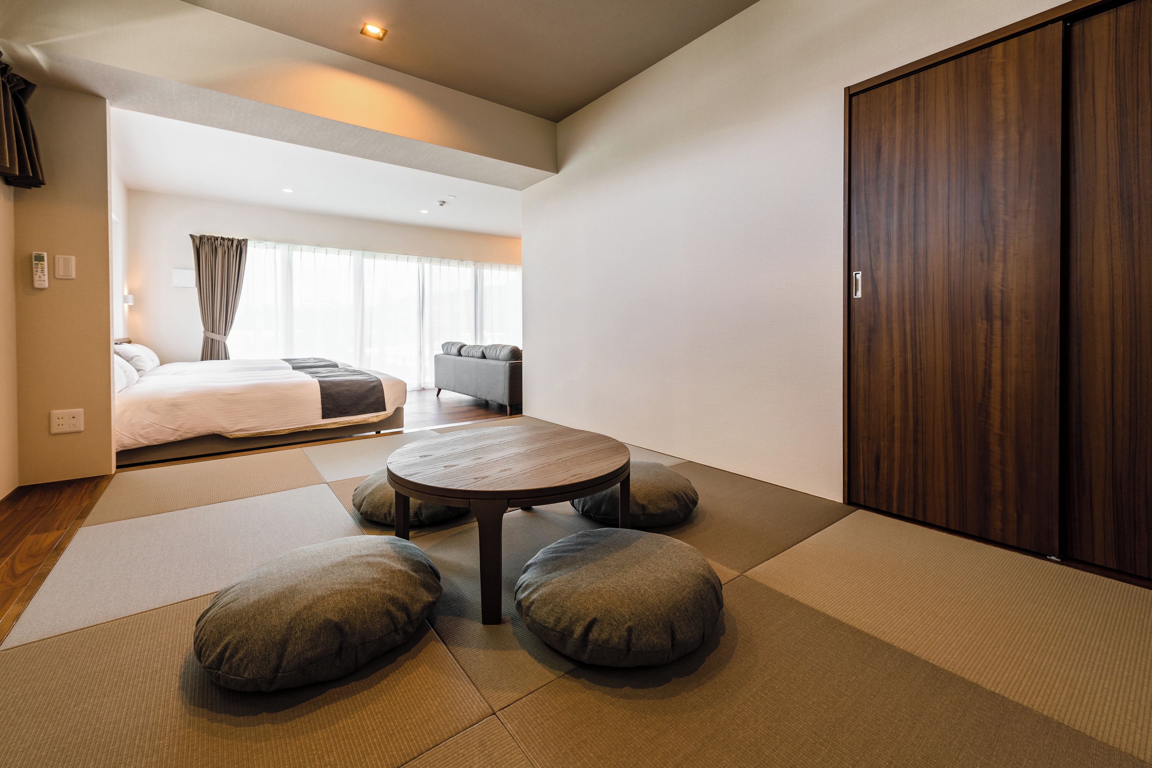 Een hotelkamer met een bed, een slaapbank, een ronde tafel en een kledingkast.
