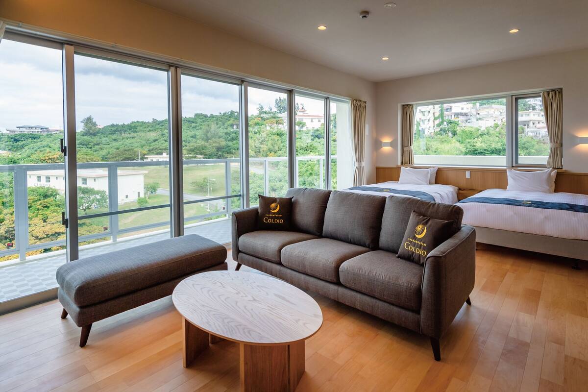A spacious room with a large bed, a sofa, and a round table.