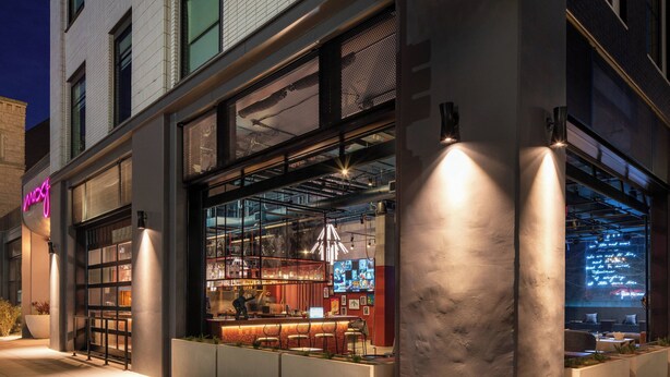 Un bar moderne doté d’une paroi vitrée, d’un espace salon et d’une enseigne au néon.