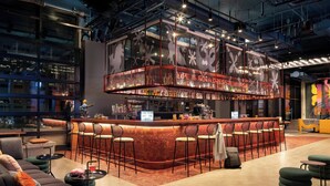 Un espace bar moderne avec un comptoir en briques rouges, de nombreux tabourets et une grande fenêtre donnant sur la ville.