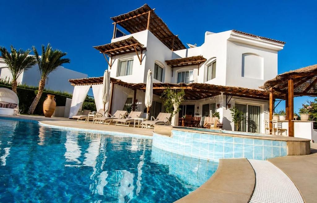 A modern villa with a swimming pool, outdoor seating, and a pergola.
