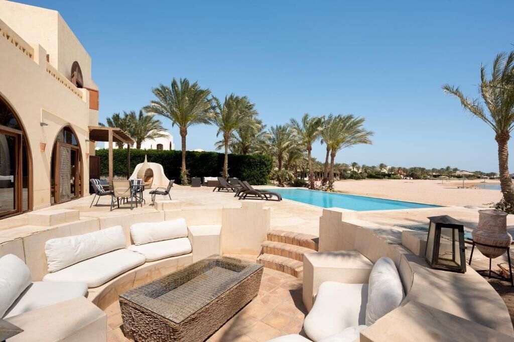 A poolside area with outdoor seating, palm trees, and a clear view of the beach.