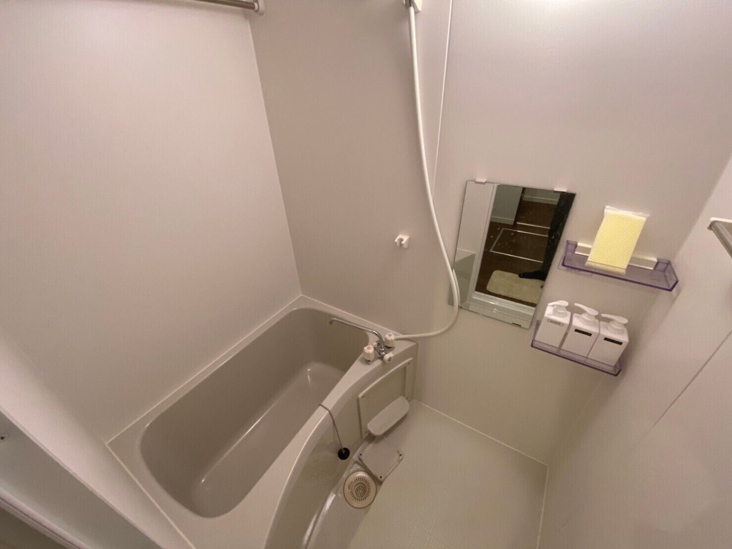 Un baño con bañera, ducha y retrete. Hay estantes con artículos de aseo.