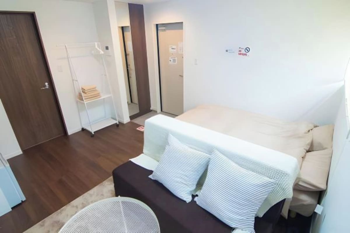 Et soveværelse med seng, sofa, et lille bord og et skab.