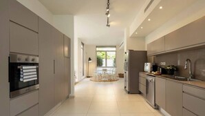 Une cuisine moderne dotée d’appareils électroménagers en acier inoxydable, un coin repas avec une table ronde et une vue sur l’extérieur.