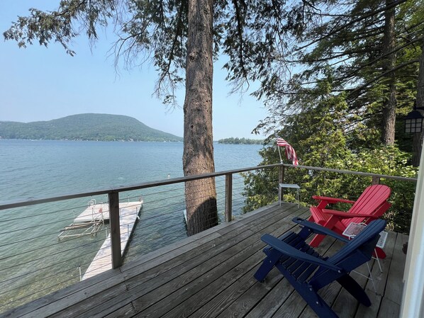 Une terrasse en bois offrant une vue sur un lac, un quai et un drapeau.