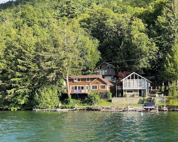 Een vakantiehuis aan het meer, met een steiger, een woning en een boot.