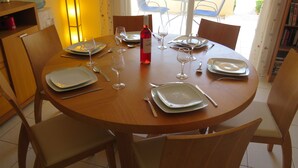 A dining table set with plates, cutlery, and wine glasses, surrounded by chairs. - G3 Polis Gardens - includes WiFi & A/C  (Polis)