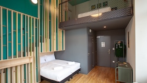 Habitación de hotel pequeña con cama, una mesita y un banco.