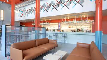 A modern bar area with a bar counter, stools, and a seating area with sofas and a coffee table.
