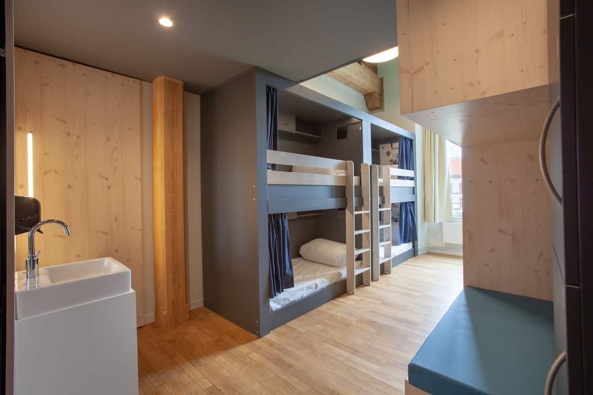 Ein Zimmer mit Etagenbetten, einem Waschbecken und Holzboden.