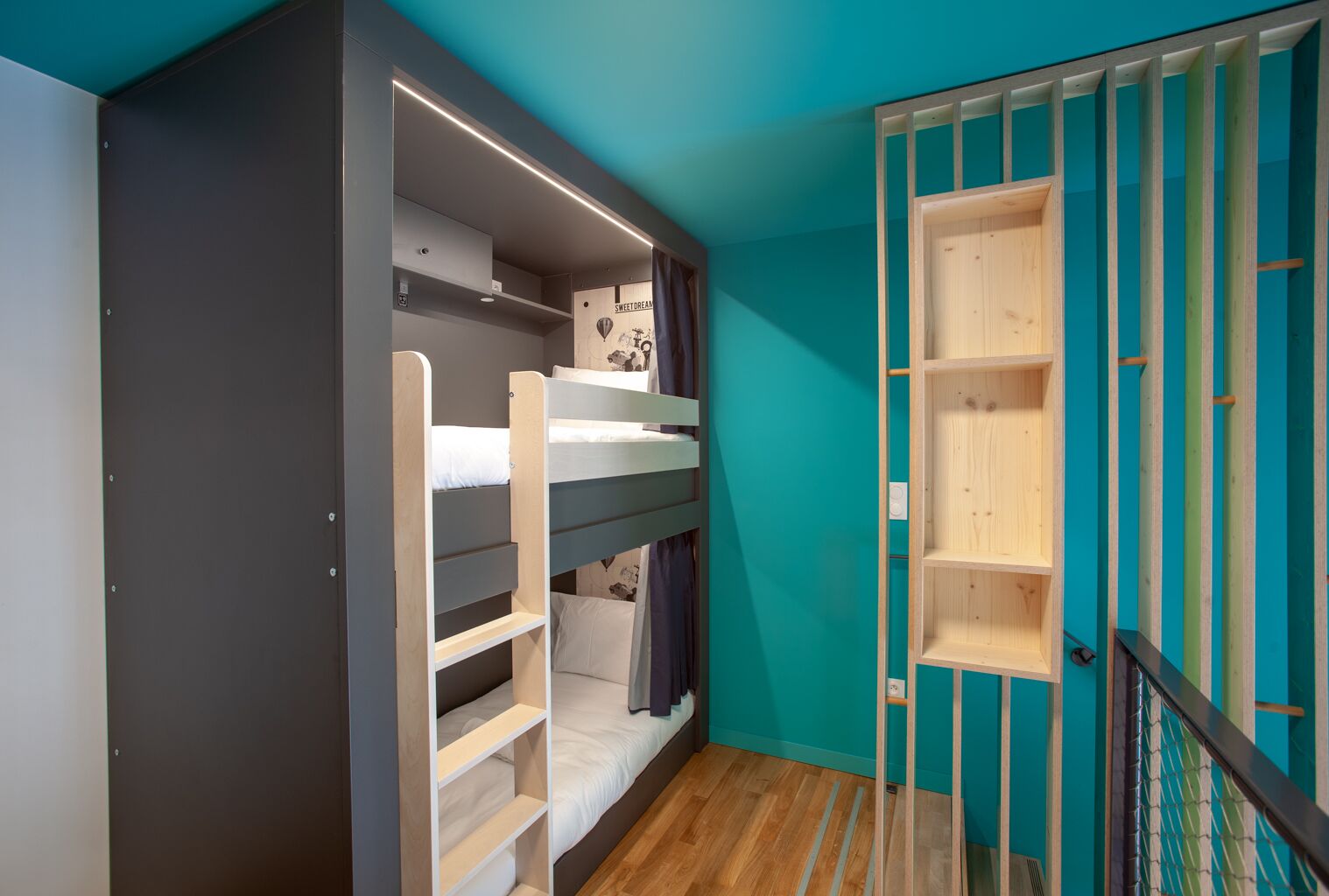 Habitación con literas, un armario, un estante pequeño y una puerta de madera.