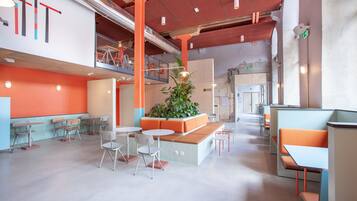 A modern interior with seating areas, a central plant, and exposed structural elements.