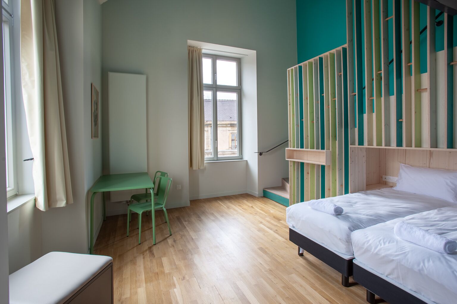 Een slaapkamer met een bed, een bureau en een stoel. Er is een raam en uitzicht op buiten.