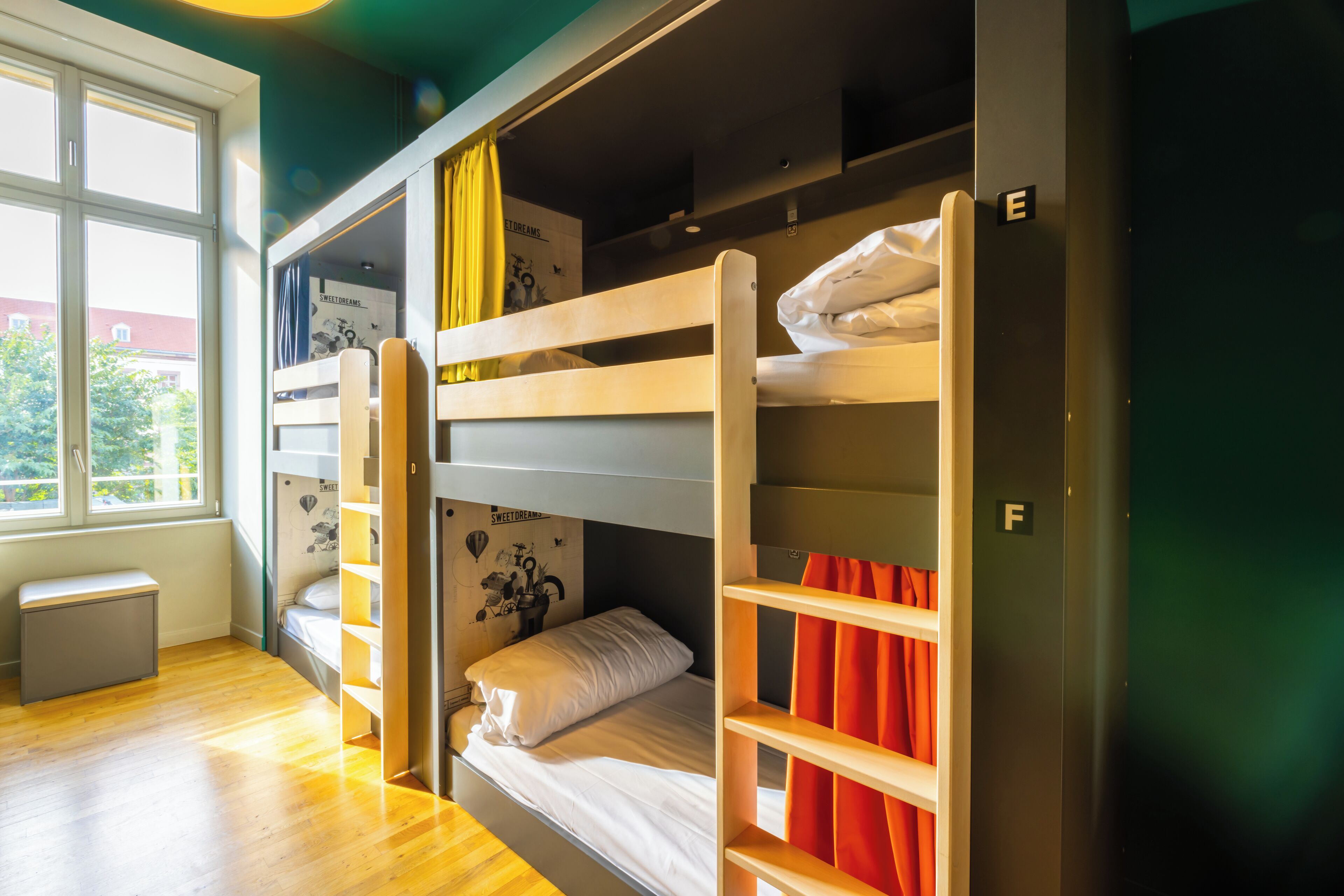 Une chambre de dortoir avec des lits superposés, une fenêtre et un petit bureau.