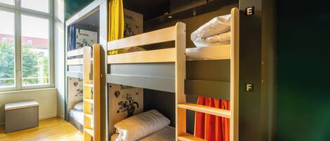 Une chambre de dortoir avec des lits superposés, une fenêtre et un petit bureau.