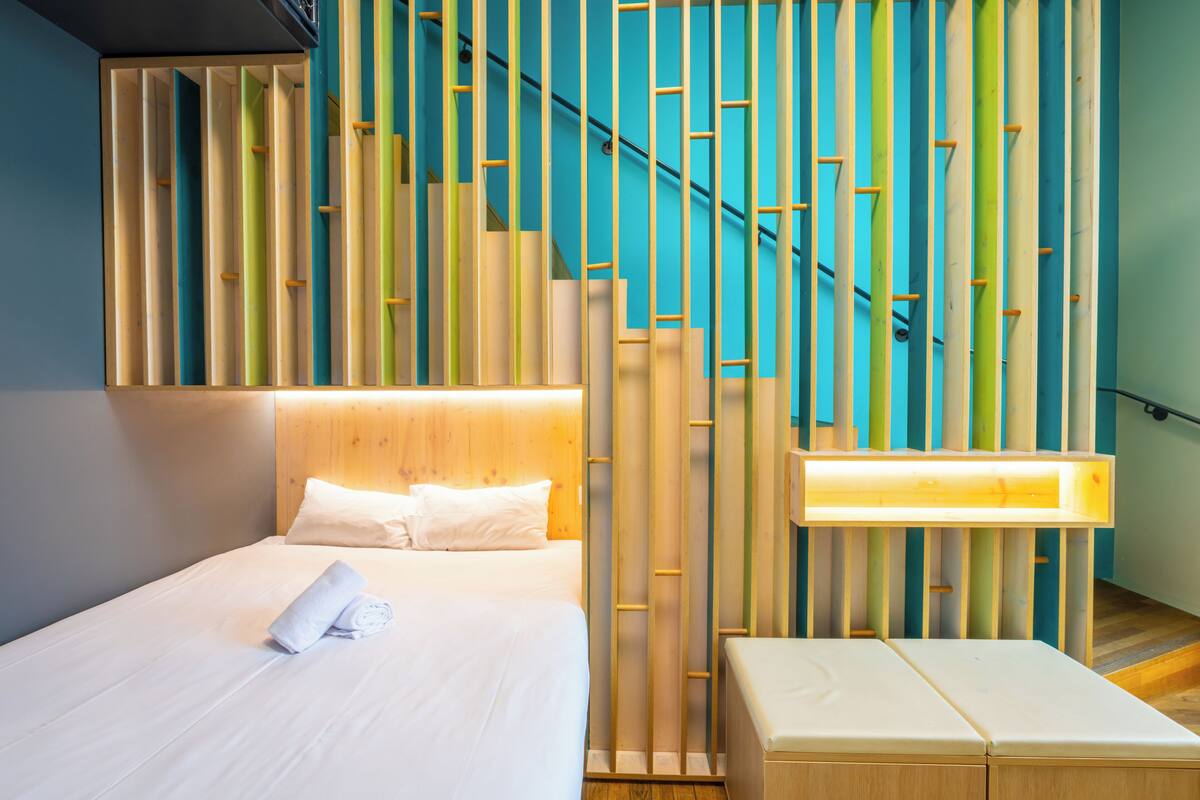 Ein modernes Hotelzimmer mit einem ordentlich bezogenen Bett, einem Holz-Kopfteil und einer Wand mit einem einzigartigen Bambusmuster.