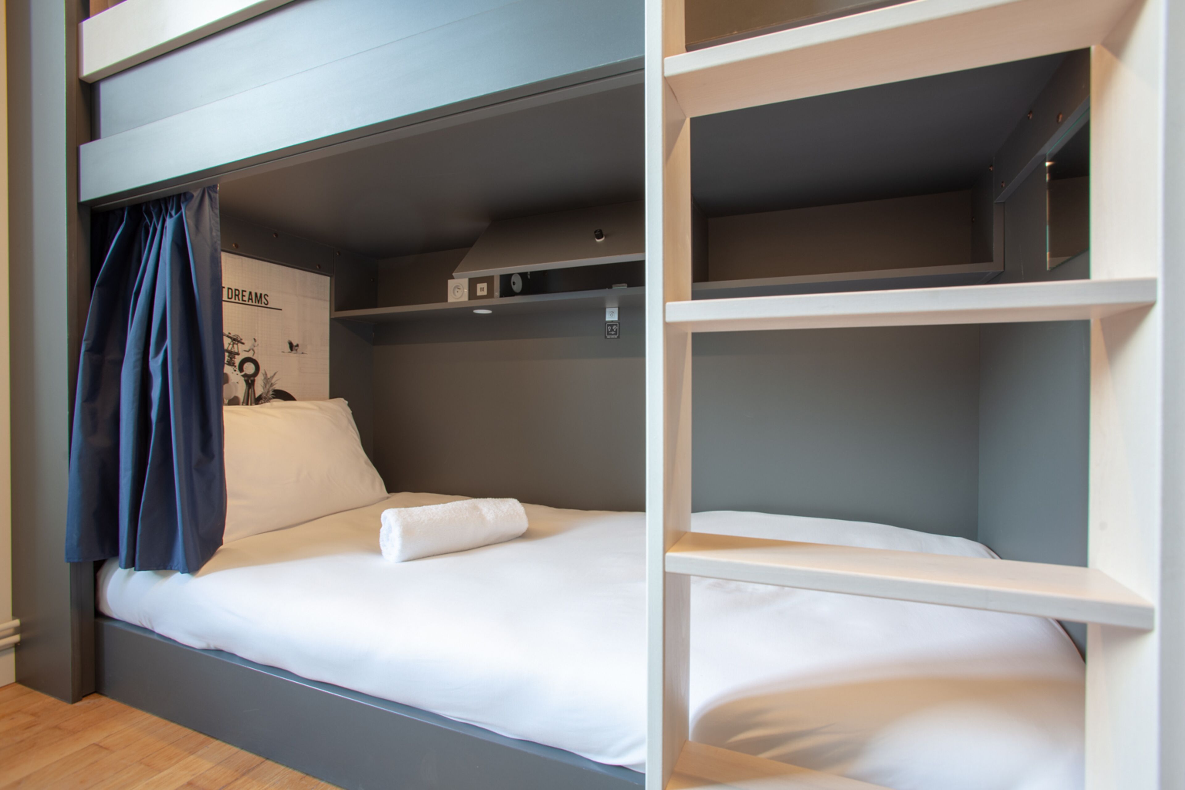 A bunk bed with a white mattress and a blue curtain.