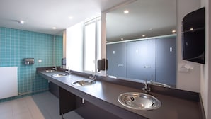 Un baño moderno con tres lavamanos, un espejo grande y una pared revestida de azulejos azules.