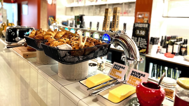 Una barra de desayuno con pasteles, queso y una máquina de café.