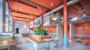 Un espacio interior amplio con arreglos de asientos, una planta central y un nivel superior con barandillas.