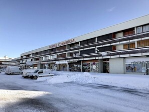 Kyseessä on kerrostalorakennus, jossa on useita kerroksia, apteekki ensimmäisessä kerroksessa ja useita parkkeerattuja ajoneuvoja rakennuksen edessä.