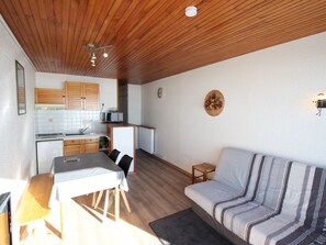 A compact living space with a kitchenette, a dining table, a sofa, and a small stool. - Studio for 4 people at the foot of the slopes in Chamrousse (Chamrousse)