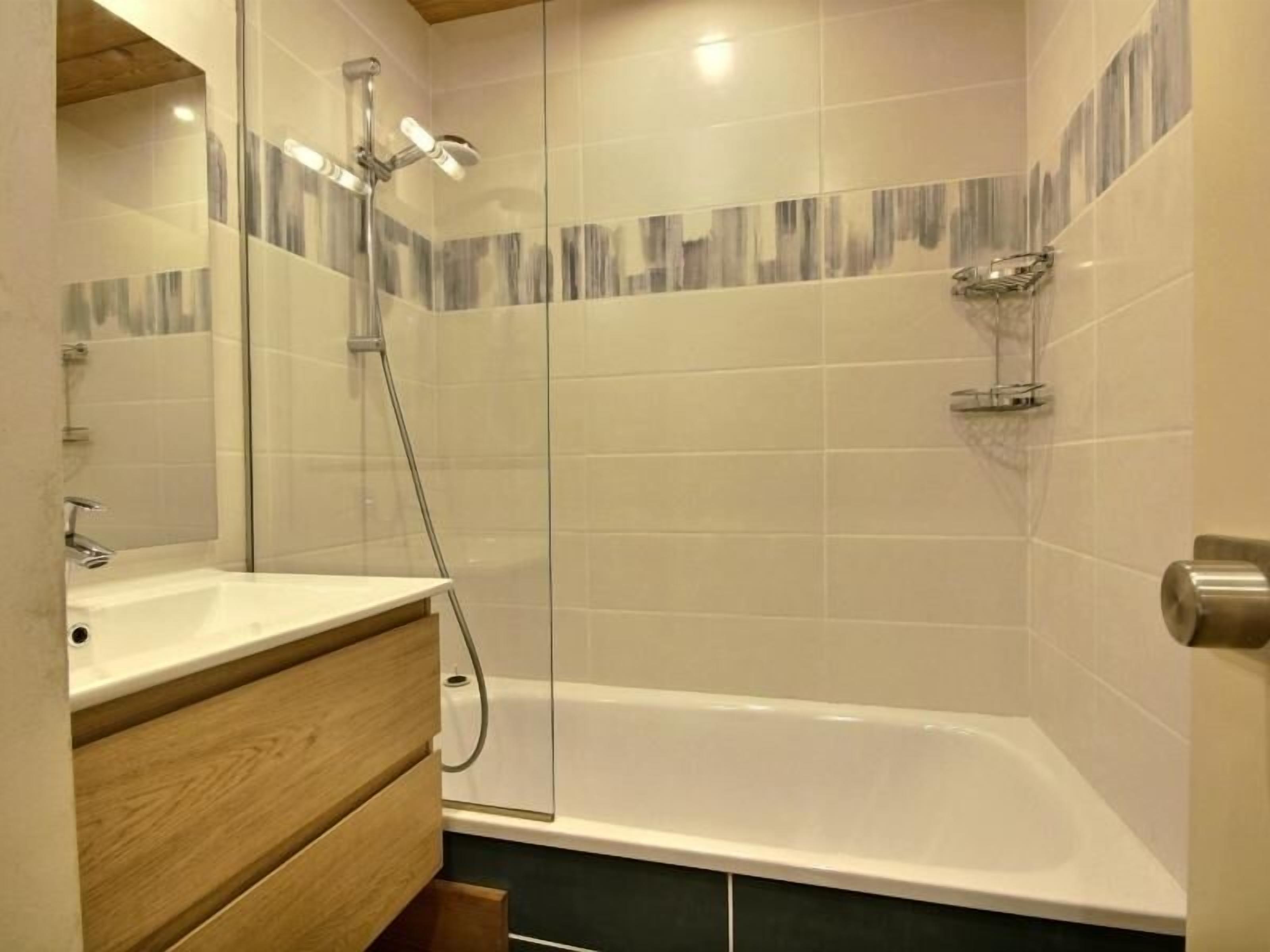 A modern bathroom with a bathtub, a wooden vanity, and a glass shower enclosure.