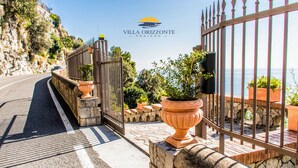 Villa Orizzonte in Praiano, mit einer Steinmauer, einem Metallgitter, Kübelpflanzen und Meerblick.