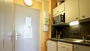 Une cuisine compacte équipée d’un four à micro-ondes, d’un lave-vaisselle et d’un évier.