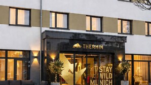 Un hôtel à l’architecture moderne, doté de grandes fenêtres et d’une enseigne bien visible indiquant « Stay Wild Munich ».