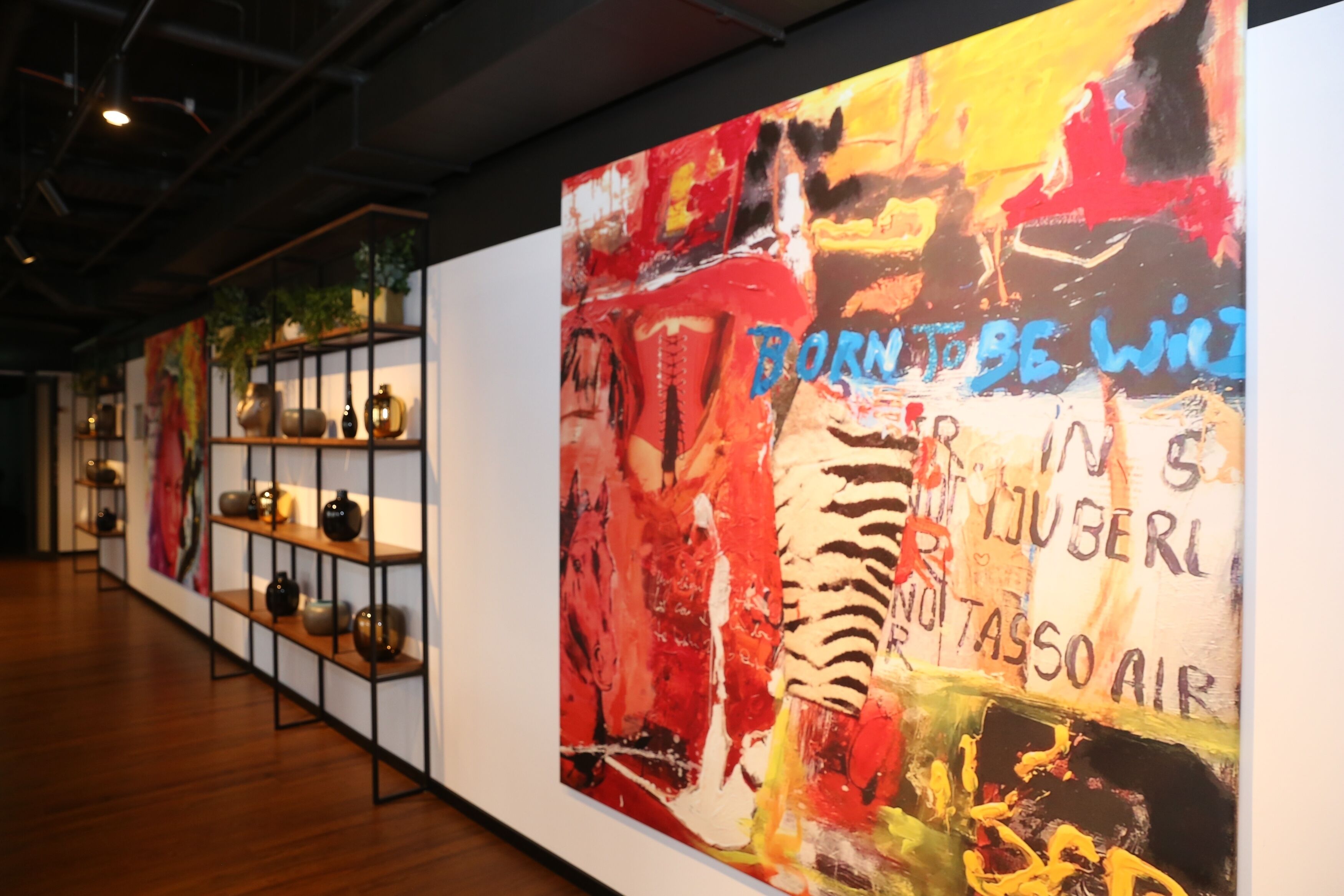 Una galleria con opere d'arte esposte, tra cui un grande dipinto astratto con testo.