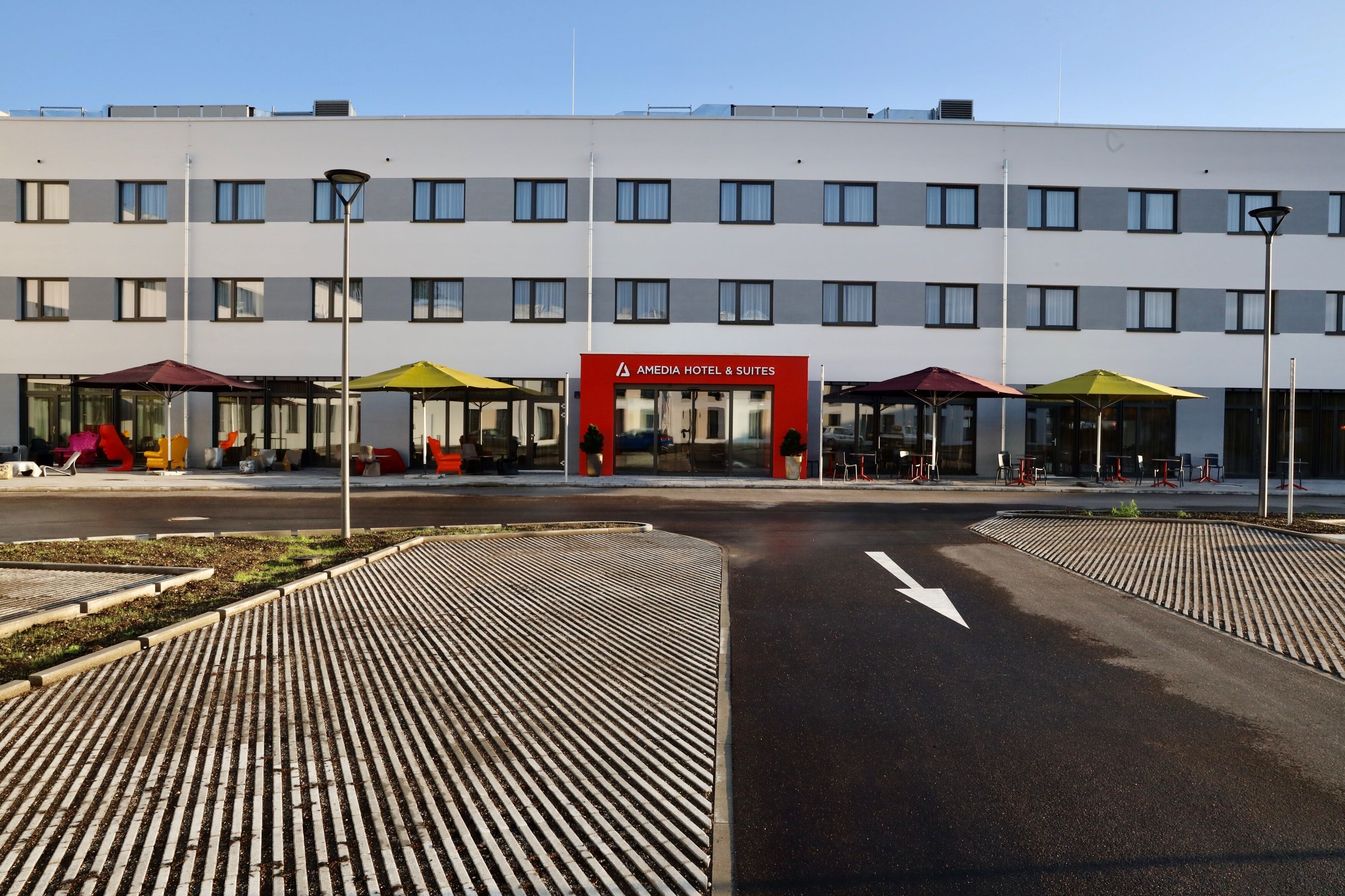 Un hotel moderno con una facciata lineare, numerose finestre e un ingresso centrale con un cartello rosso.