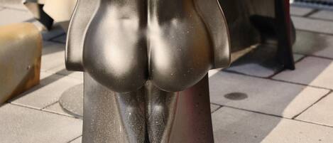 Una escultura metálica de forma singular, sobre un piso de baldosas.
