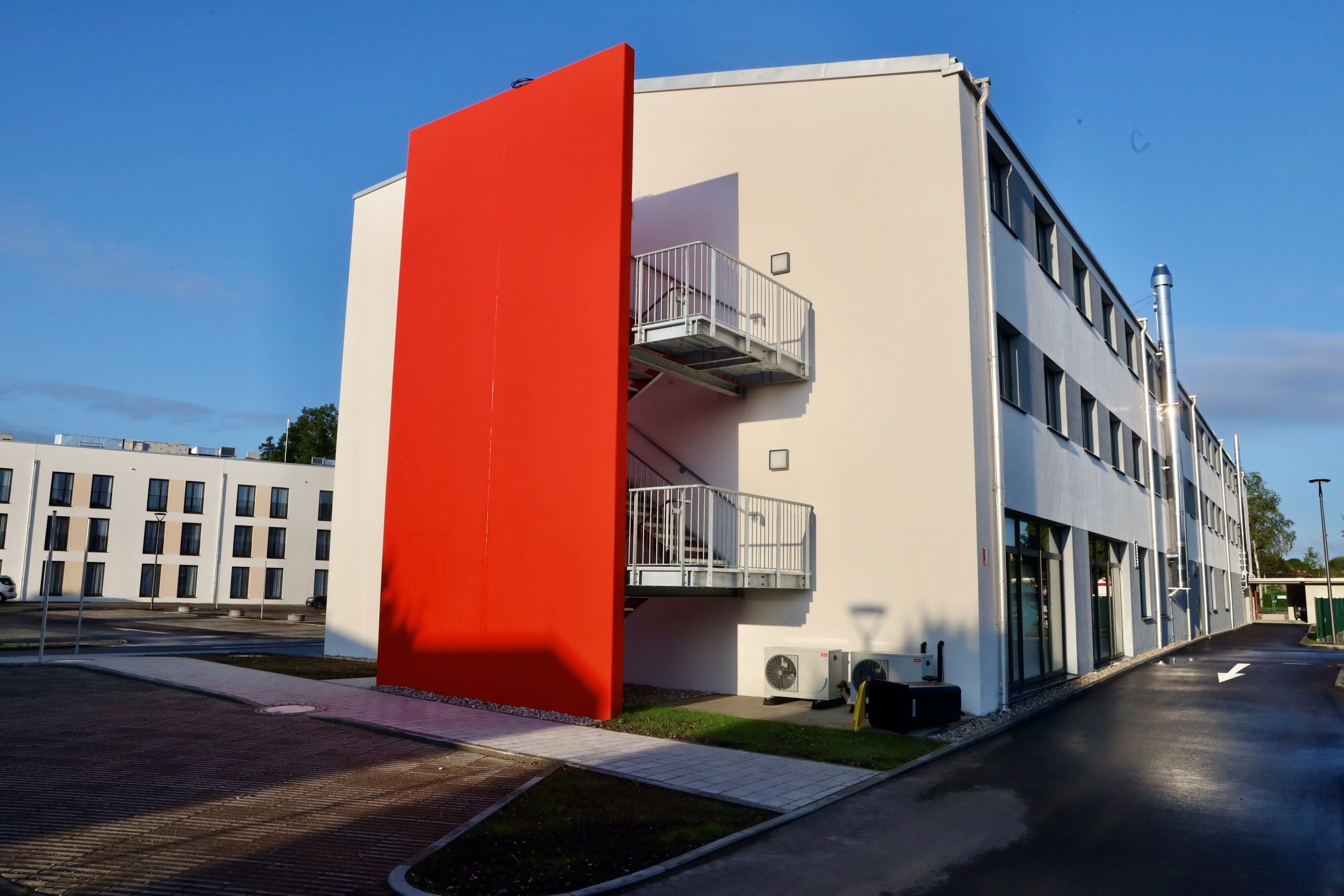 Un edificio moderno con fachada roja y un balcón.