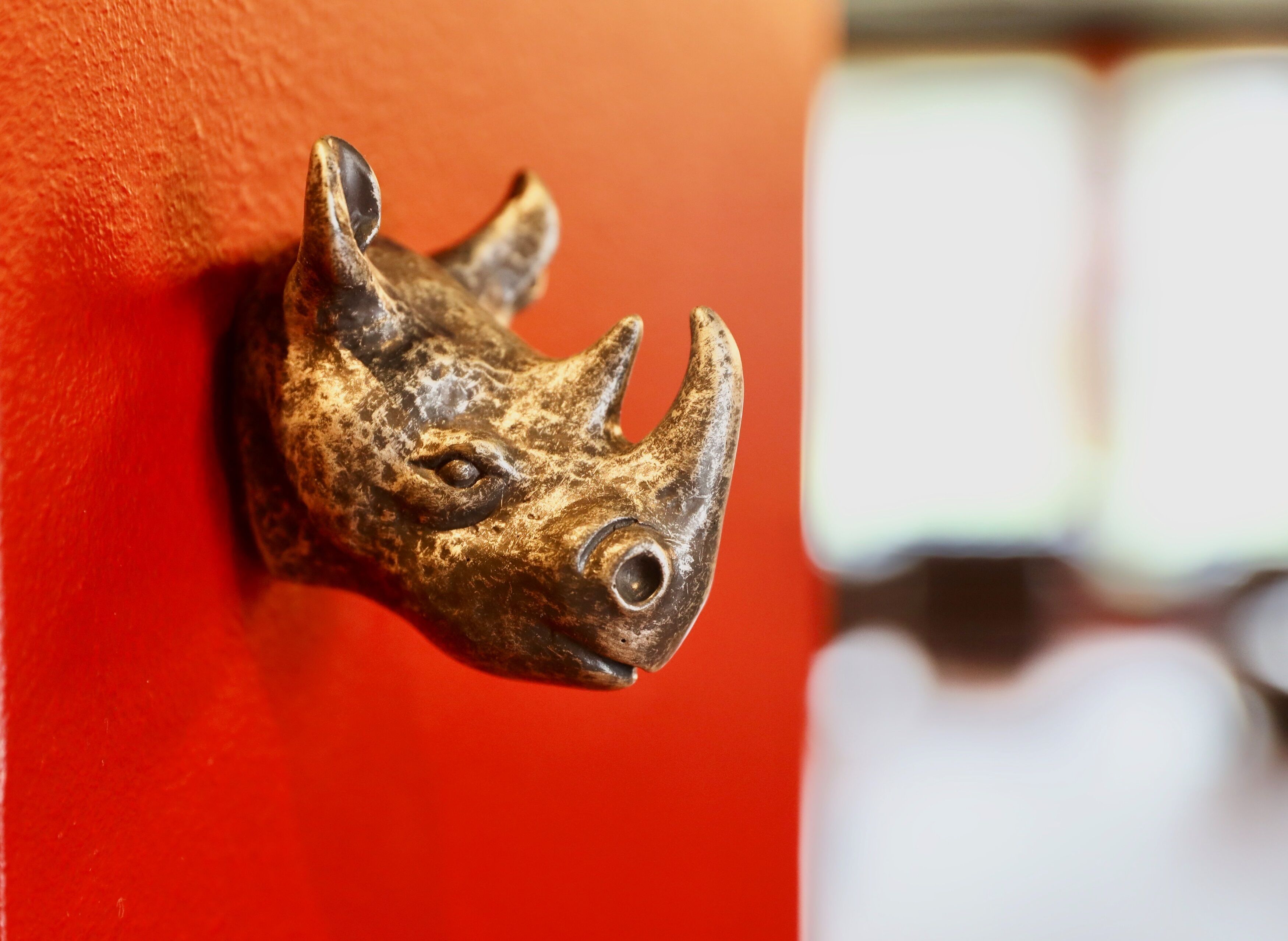 A close-up of a bronze animal head mounted on a red wall.