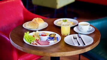 Una mesa con alimentos para el desayuno, como pan, una bebida y una taza de café.